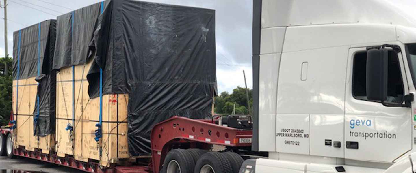 Geva truck transporting oversize cargo on RGN trailer